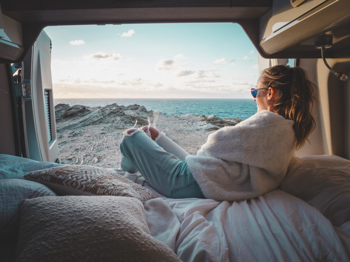 Woman looking out the open window of an RV at Pacific Coast view