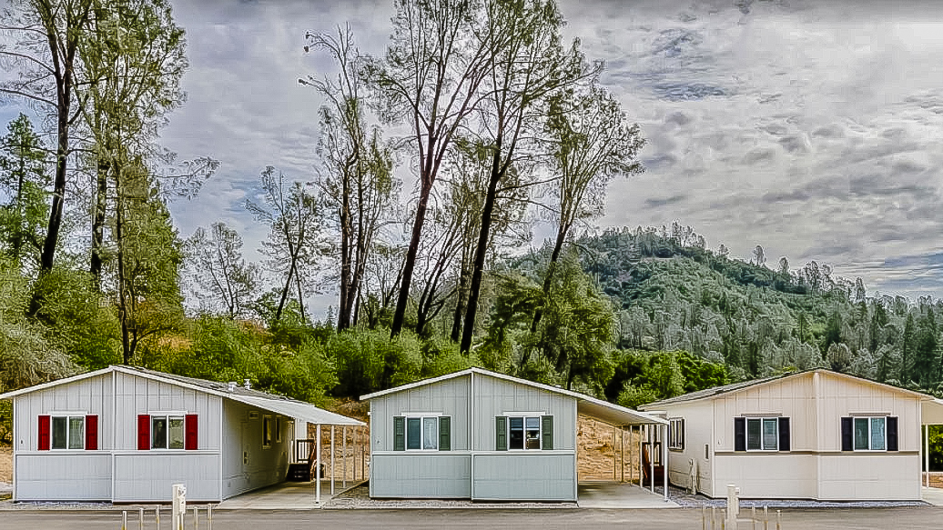 Three manufactured homes in Mountain Gate Manufactured Home Community in Redding, CA with trees and mountains in the background